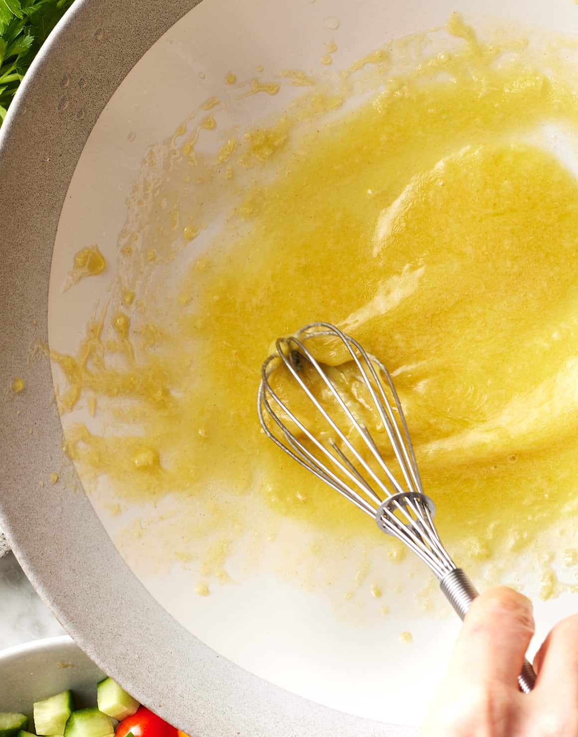 Hand whisking lemon dressing in large bowl